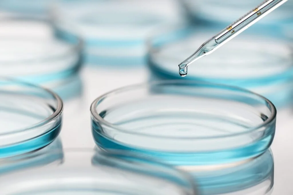 Una pipetta rilascia una goccia di liquido blu in una capsula di Petri durante un'analisi per l'industria conciaria.