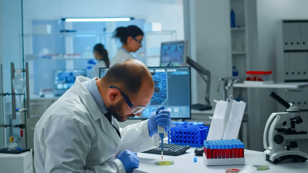 Un ricercatore utilizza una pipetta su una piastra di Petri in un laboratorio di ricerca scientifica.