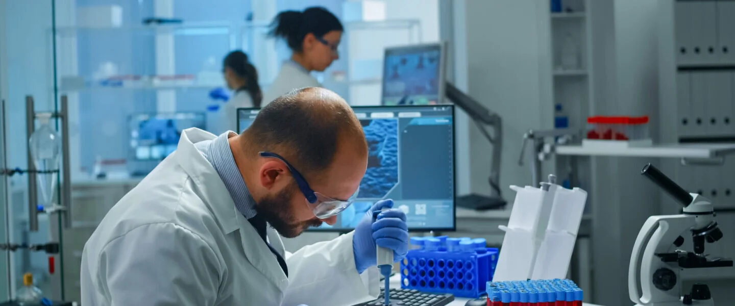Un ricercatore utilizza una pipetta su una piastra di Petri in un laboratorio di ricerca scientifica.