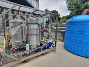 Impianto industriale in acciaio inox con serbatoio blu per il trattamento acque utilizzato in progetti di ricerca.