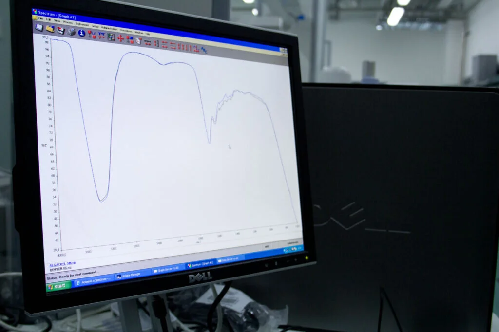 Monitor di un computer che mostra un grafico di spettroscopia infrarossa con curve di analisi chimica.