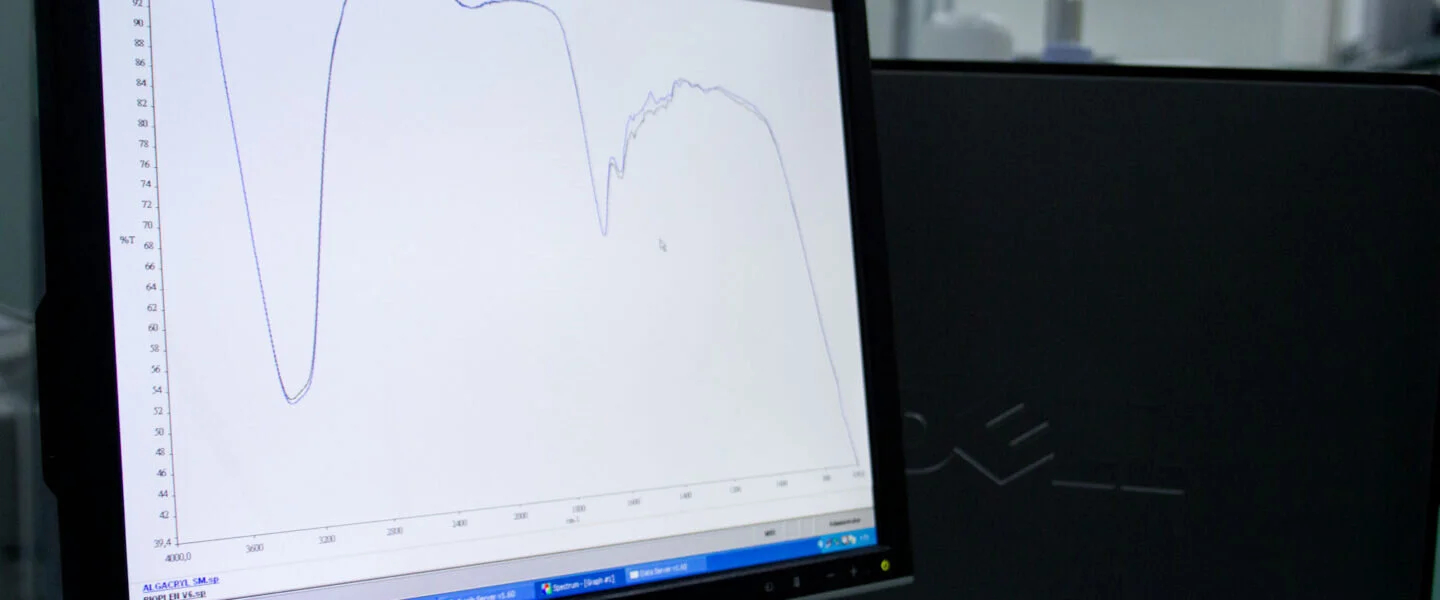 Monitor di un computer che mostra un grafico di spettroscopia infrarossa con curve di analisi chimica.